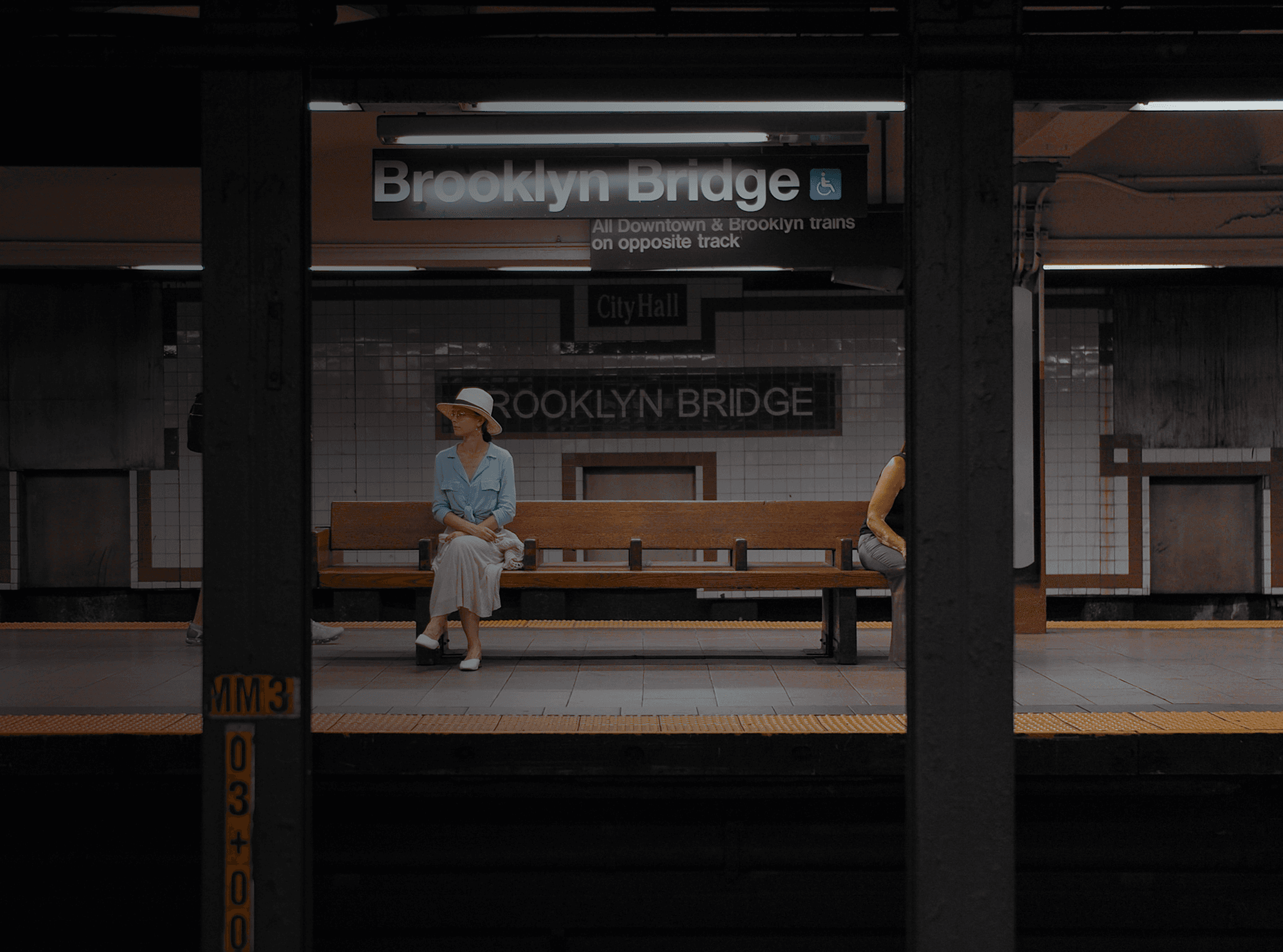 Una mujer se sienta en un banco en una estación de metro.