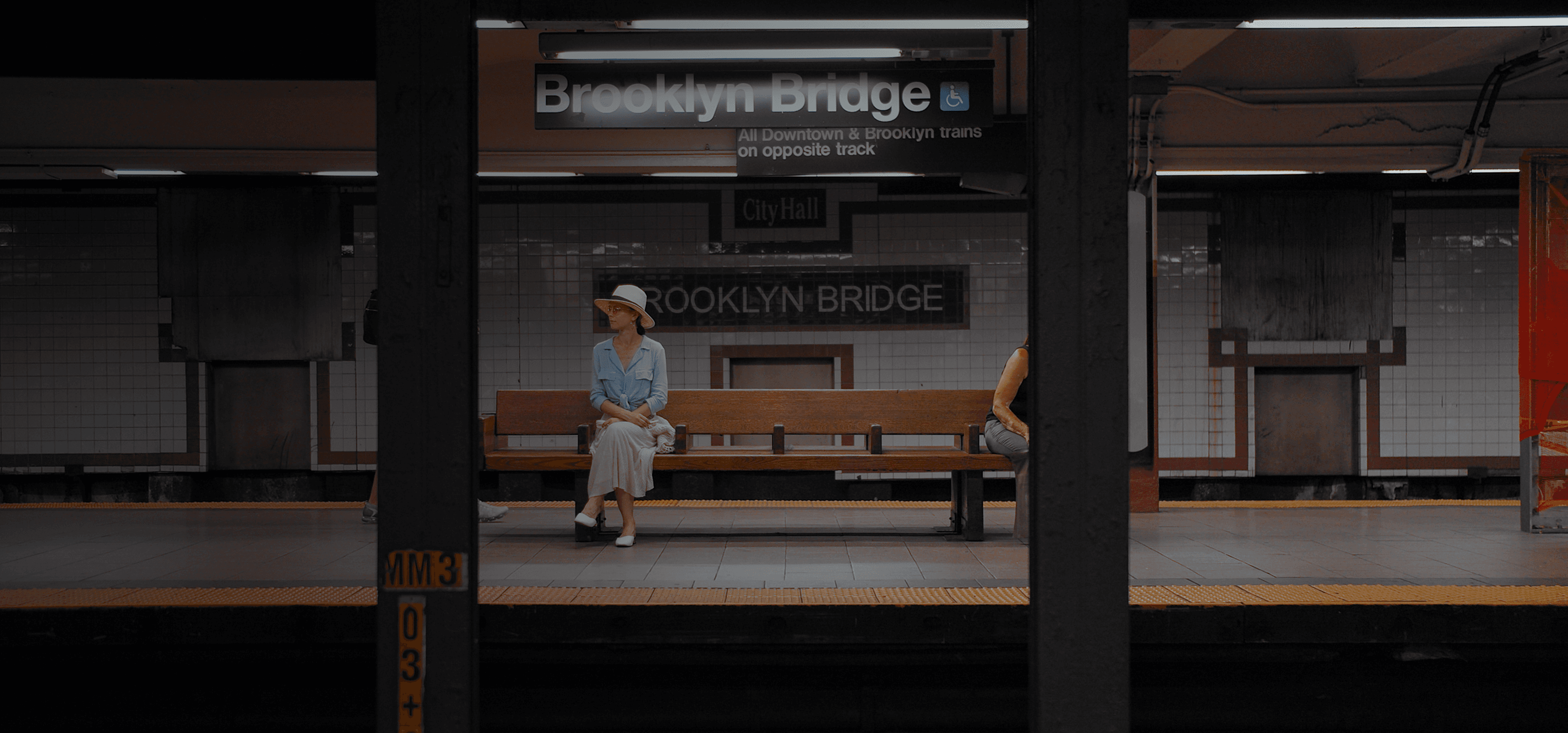 Una mujer se sienta en un banco en una estación de metro.