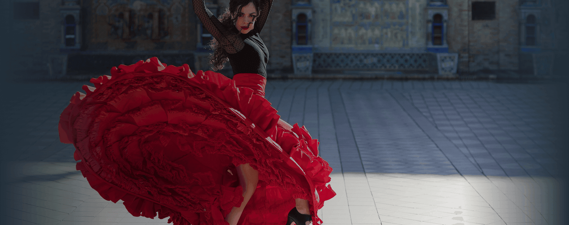 Flamenco dancer spins in front of majestic building backdrop. Overlaid is the Spanish word “bailar” with its English translation, "to dance".