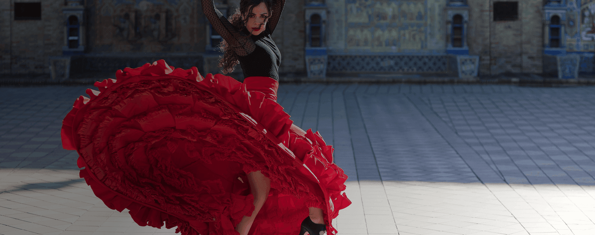 Flamenco dancer spins in front of majestic building backdrop. Overlaid is the Spanish word “bailar” with its English translation, "to dance".