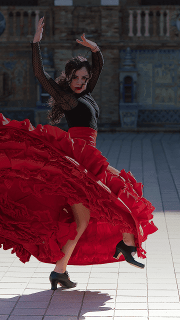 Flamenco dancer spins in front of majestic building backdrop. Overlaid is the Spanish word “bailar” with its English translation, "to dance".