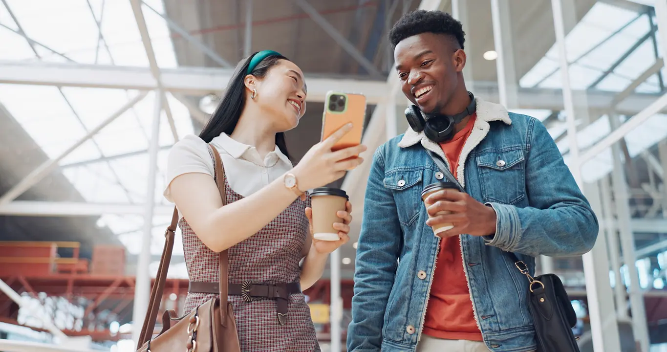 Dos estudiantes sonriendo y mirando el celular representan las soluciones de aprendizaje de idiomas de Rosetta Stone para escuelas, que promueven el aprendizaje interactivo y el aprendizaje móvil.