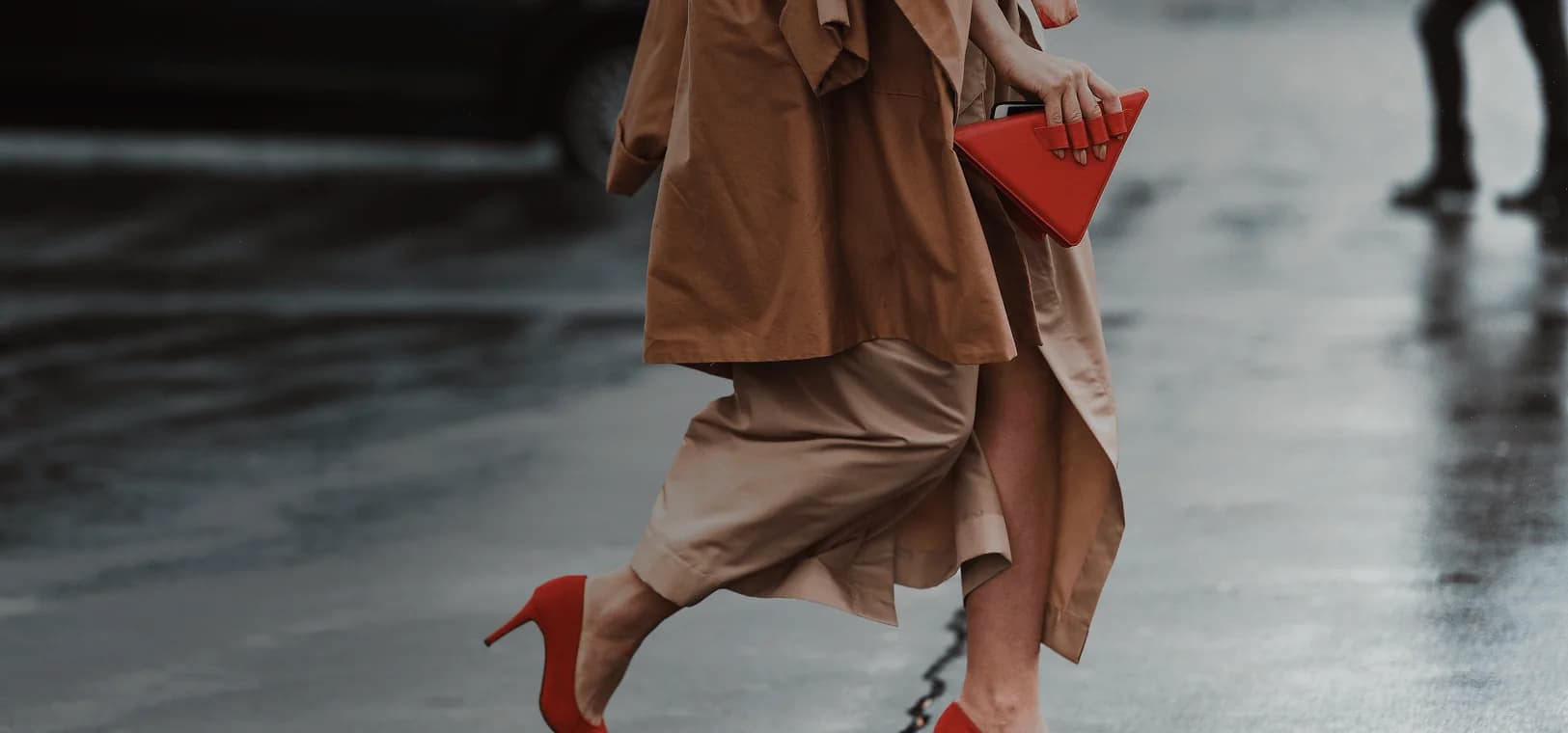 Una mujer bien vestida, con hermosos tacones altos rojos y un bolso rojo de moda, cruza la calle. Se superpone la frase francesa "bien habillé" con su traducción al español, "bien vestido".